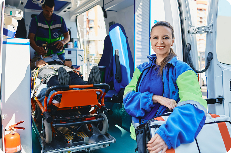 Técnica de emergencias junto a la puerta de una ambulancia con un paciente en la camilla